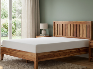 Wooden bed with white mattress in a room with green walls and a window.