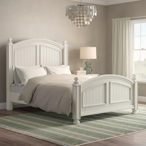 White bedroom with a bed, lamp, and striped rug.