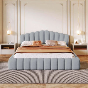 Gray upholstered bed with decorative pillows and a striped blanket in a bedroom setting.